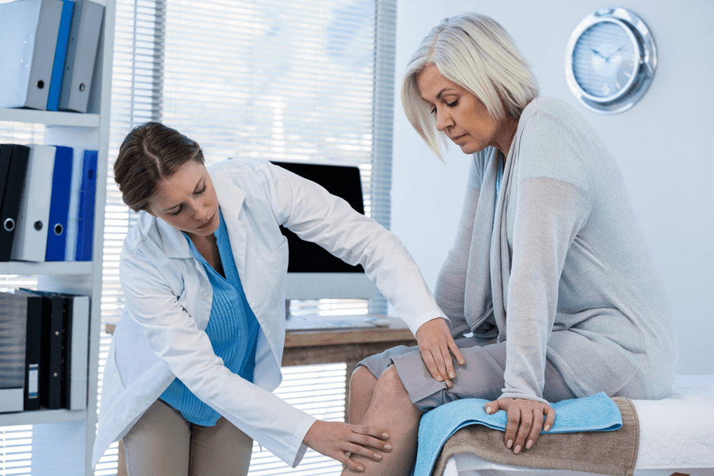 De arts onderzoekt een patiënt met artrose van het kniegewricht